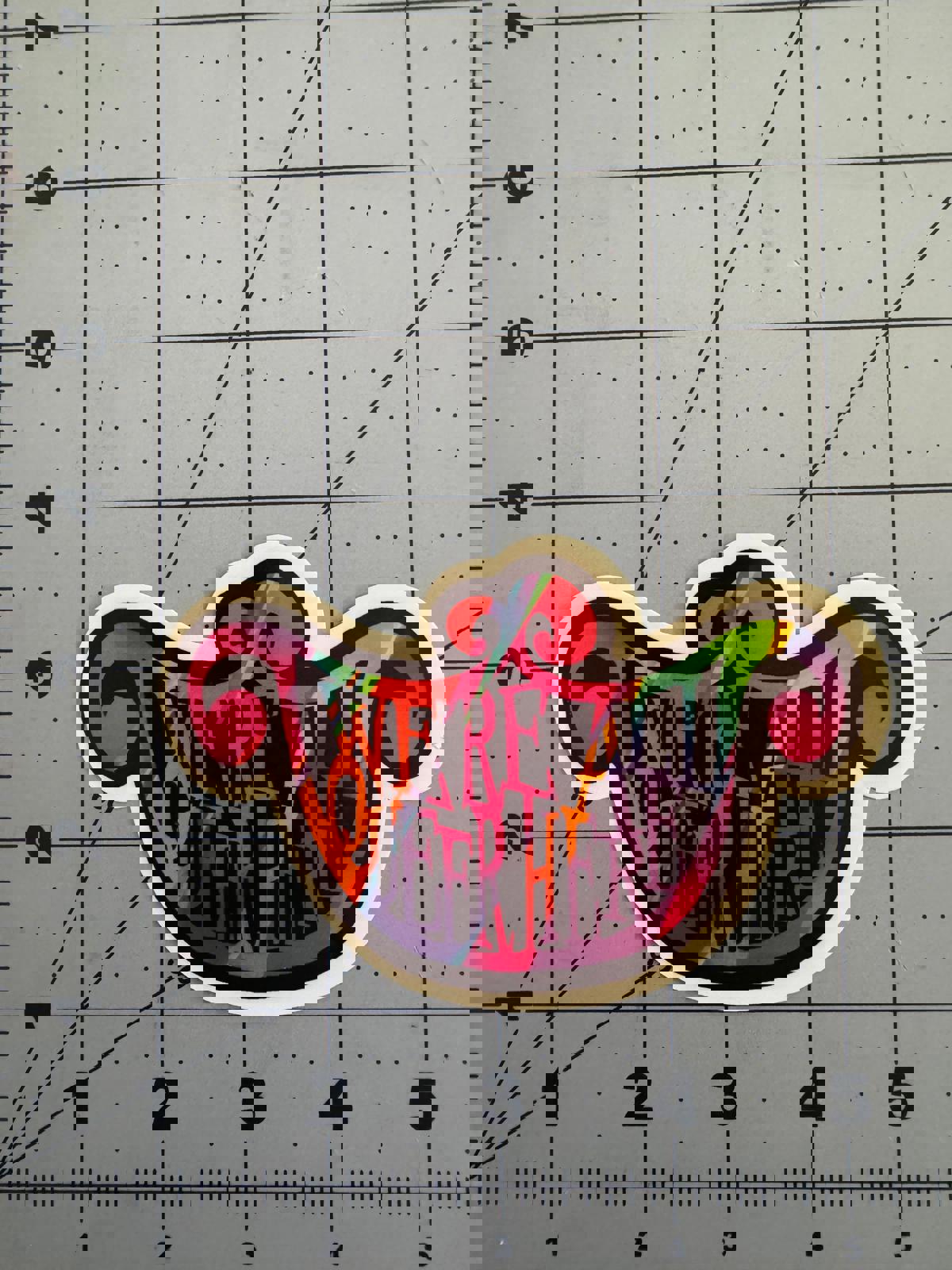 “We’re All Queer Here” Rainbow Cheshire Cat Smile Sticker – Holographic and Classic White Options