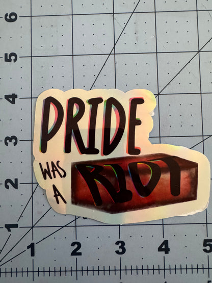 Sticker reading “Pride Was a Riot” with the word “Riot” stylized as a red brick. Available in holographic and classic white finish.
