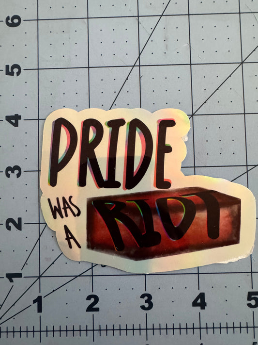 Sticker reading “Pride Was a Riot” with the word “Riot” stylized as a red brick. Available in holographic and classic white finish.
